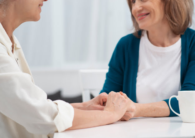A doctor and patient holding hands at a table while discussing getting sober in Asheville, North Carolina.