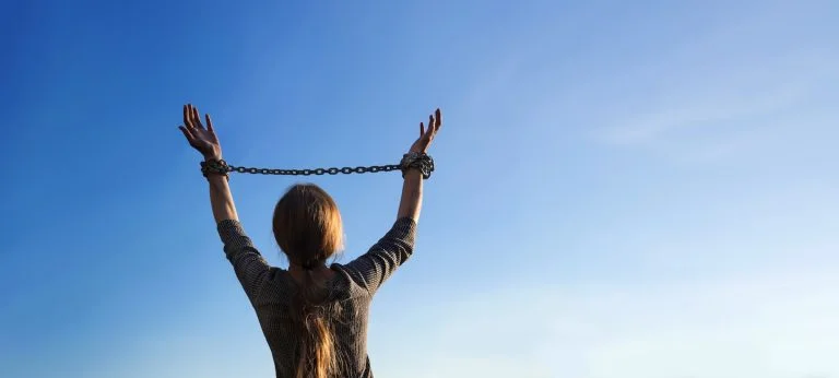 A person with chains around their wrists raising them towards the sky symbolizing getting help and breaking free from drug abuse in North Carolina.
