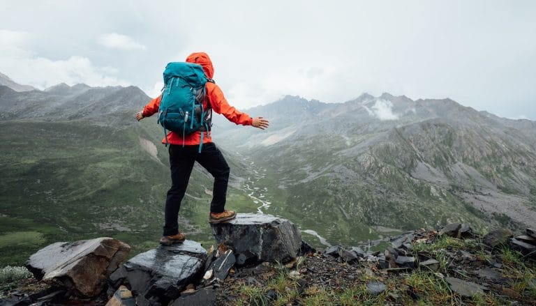 Hiking woman on high altitude mountain top, symbolizing addiction recovery success.